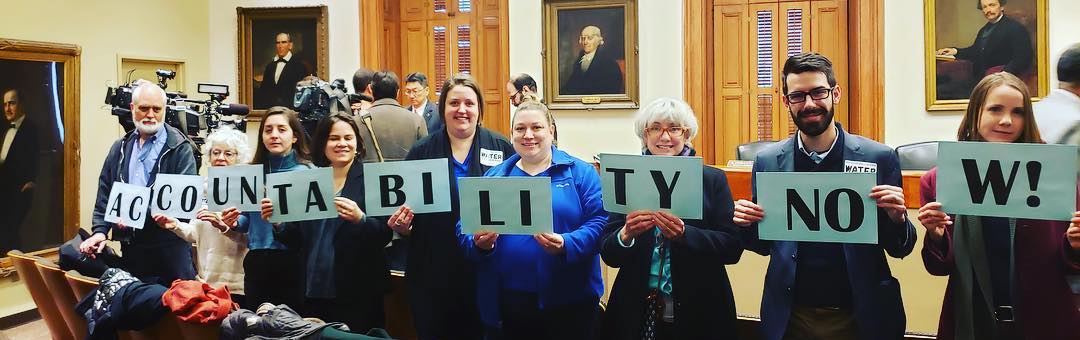 people holding signs with letters that reads ACCOUNTABILITY