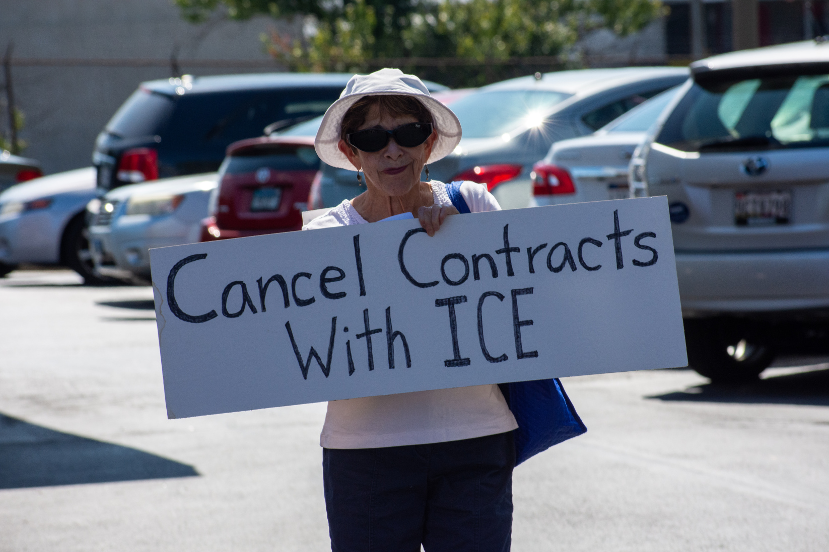 woman holds sign reading "cancel contracts with ice"