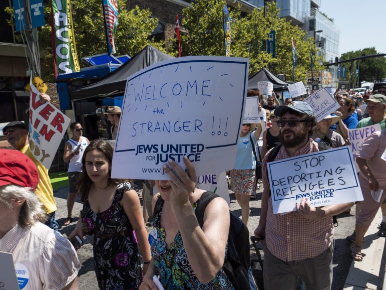 woman holding sign reading welcome the stranger