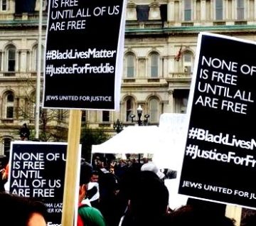 Signs: None of us is free until all of us are free. #BlackLivesMatter #JusticeForFreddie