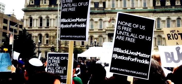Signs: None of us is free until all of us are free. #BlackLivesMatter #JusticeForFreddie