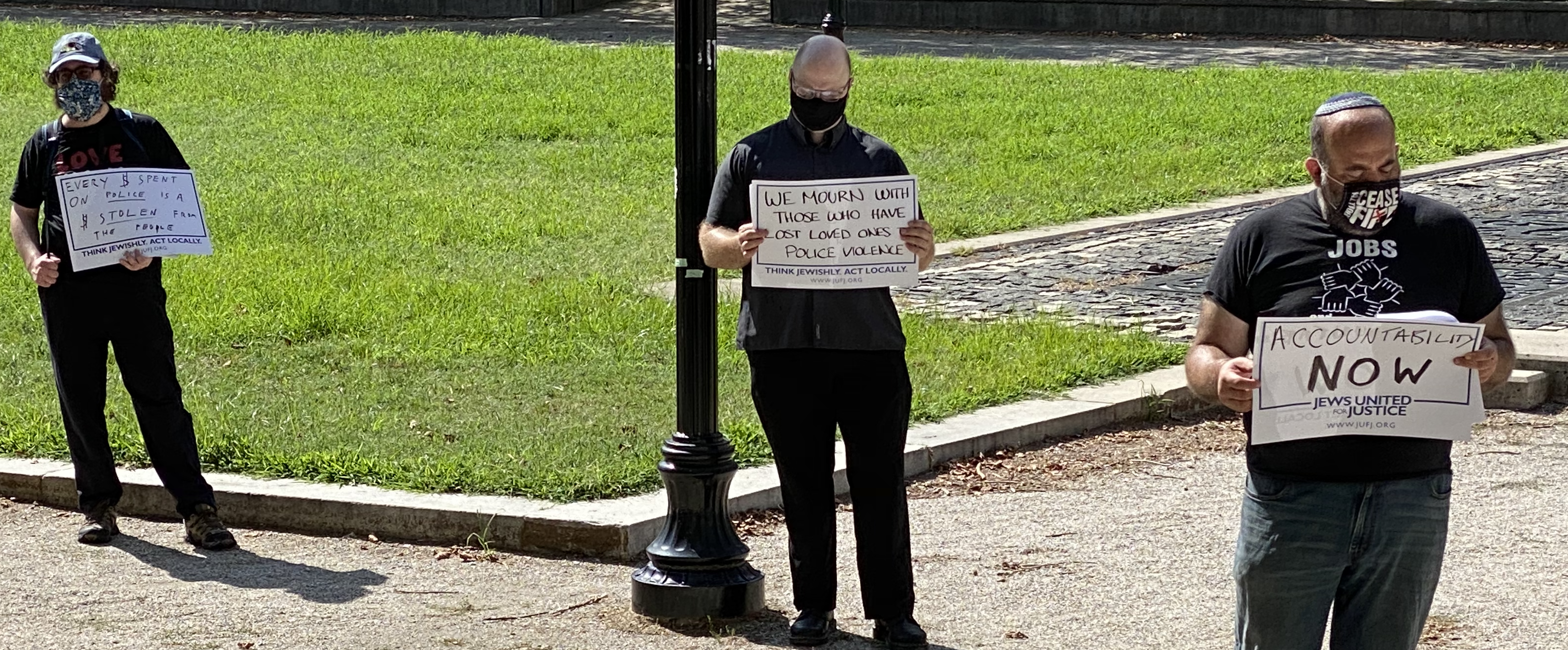 tishabavbmore2020 Three JUFJers in all black hold signs outdoors