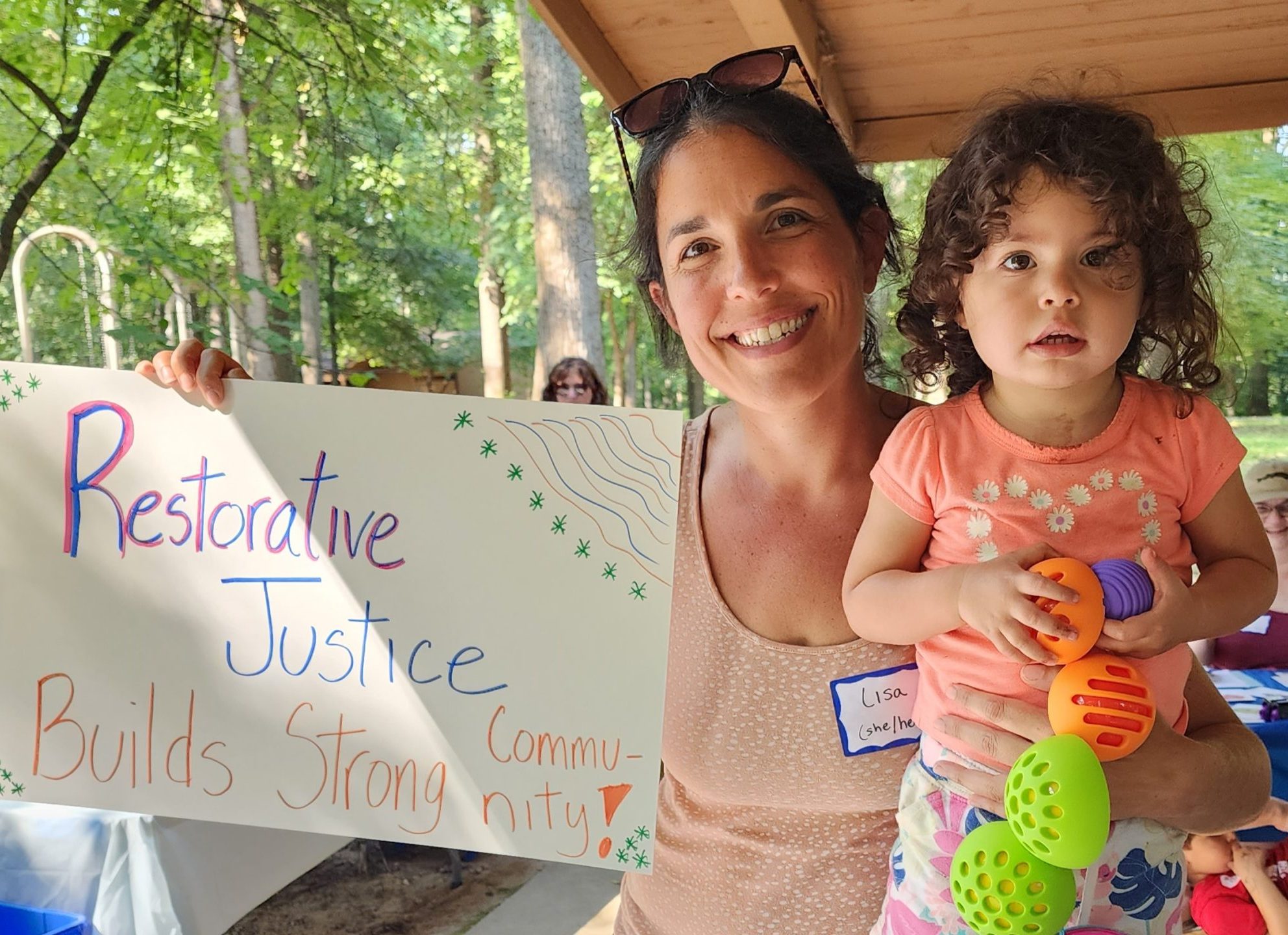 Lisa and her daughter with a sign: Restorative Justice Builds Strong Community!